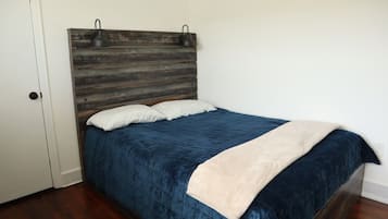 Une chambre à coucher avec une tête de lit en bois, une couvre-lit bleue et un oreiller blanc.