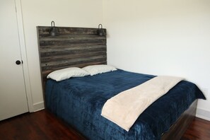 A bedroom with a wooden headboard, a blue bedspread, and a white pillow.