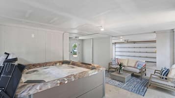 Ein moderner Spa-Bereich mit Whirlpool, Sitzgelegenheit und Blick auf die Garage.