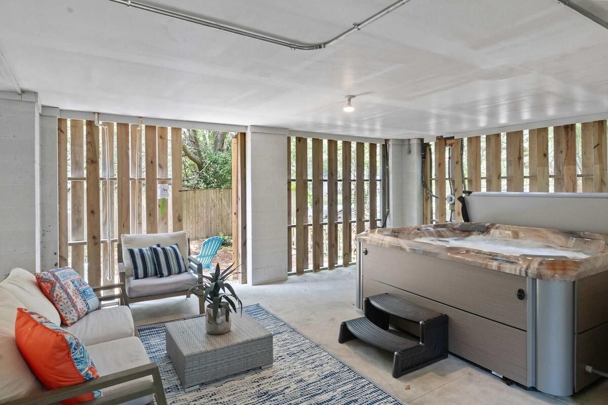 A modern outdoor living area with a hot tub, seating, and a view through wooden slats.