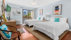 A hotel room with two beds, a desk, a chair, a ceiling fan, and artwork on the walls. - Magic Myrtle, On the Beach, Pet Friendly (Myrtle Beach)