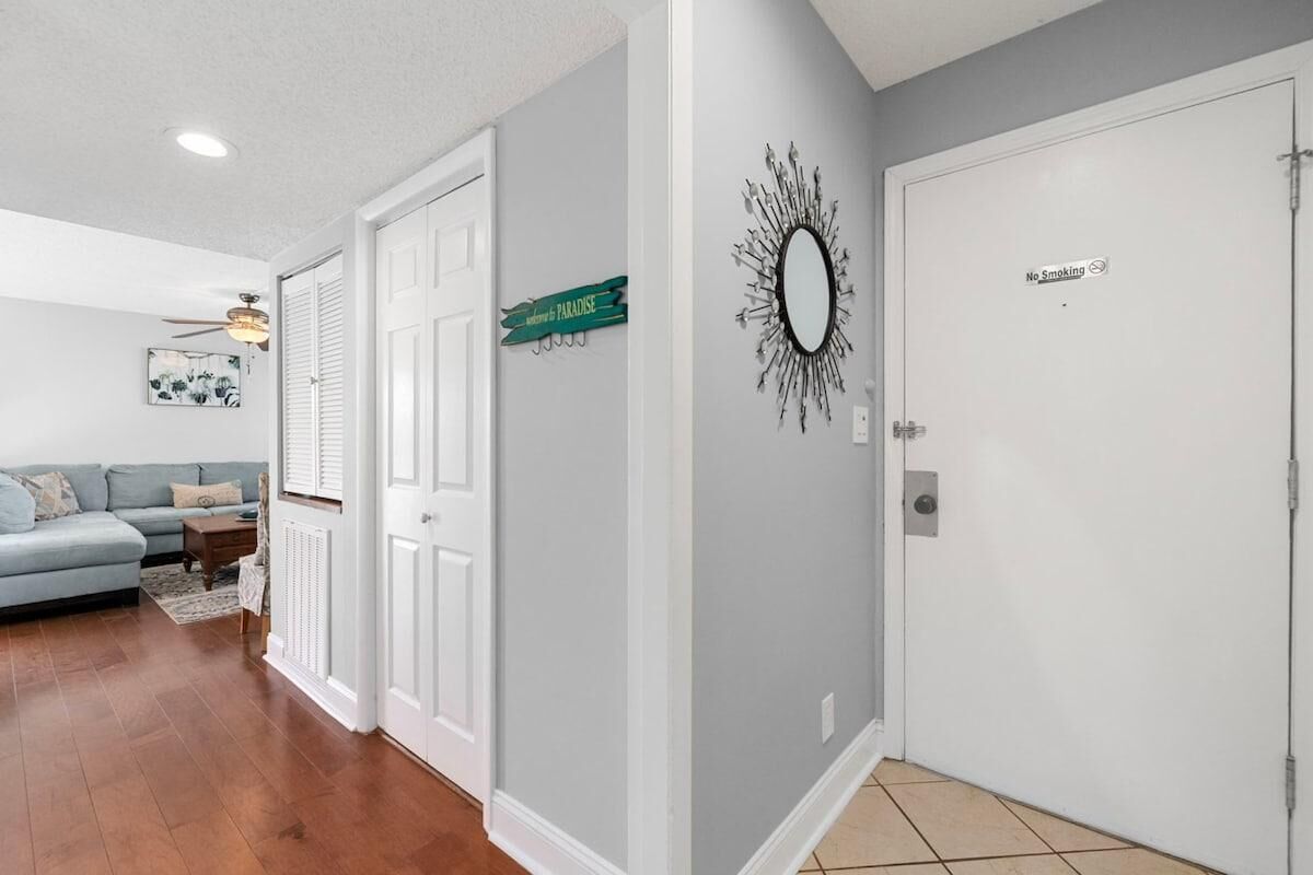 A hallway with a white door marked "No Smoking," a decorative mirror, and a sign that reads "Welcome to Paradise."