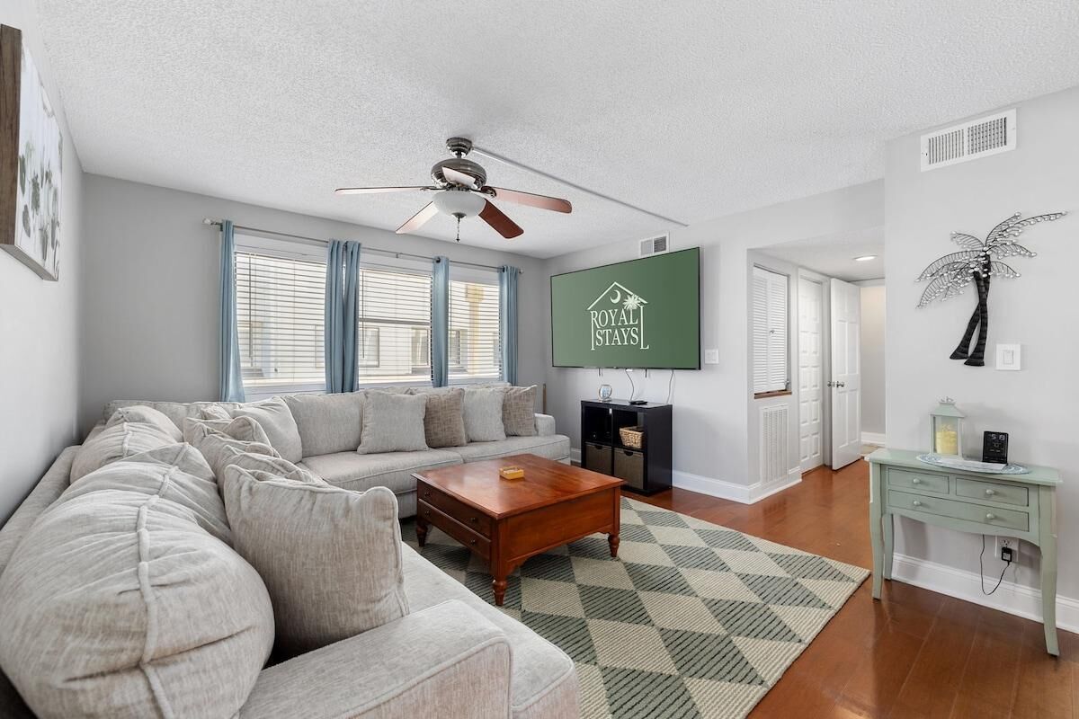A living room with a sofa, coffee table, and a TV mounted on the wall.
