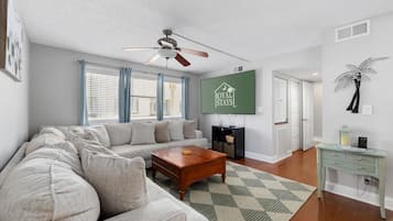A living room with a sofa, coffee table, and a TV mounted on the wall.