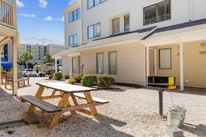A patio area with a picnic table, a barbecue grill, and a gravel ground. - Magic Myrtle, On the Beach, Pet Friendly (Myrtle Beach)