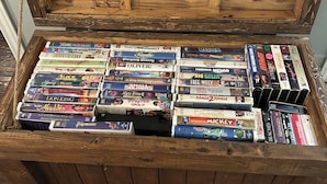 A wooden chest filled with various VHS tapes.