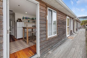 A wooden house with a kitchen area visible through an open door, featuring a refrigerator, a sink, and a dining table with stools. - The Folly Feeling, 1 Block to Beach (Folly Beach)