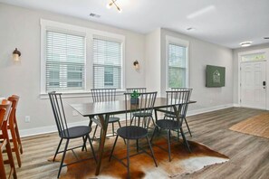 Un comedor con una mesa rectangular, cuatro sillas y un tapete de cuero de vaca.