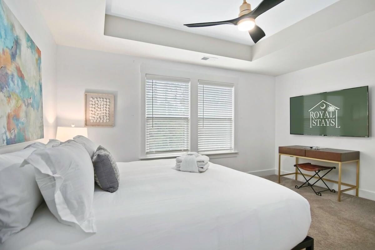 A bedroom with a bed, a desk, a chair, and a television.