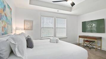 A bedroom with a bed, a desk, a chair, and a television.