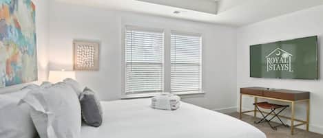 Un dormitorio con cama, escritorio, silla y televisor.