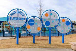 Un letrero de parque infantil con varios paneles circulares, cada uno con logotipos y texto.