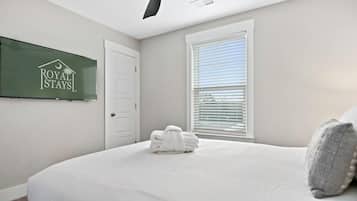 Una camera d'albergo con un letto, una ventola a soffitto, una finestra con persiane e un cartello appeso al muro.