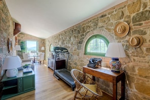 A room with stone walls, a treadmill, wicker furniture, and a desk with a typewriter and lamps. - Villa Pellegrini in Montecarlo (Montecarlo)