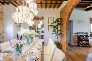 A dining area with a long wooden table set for a meal, surrounded by white upholstered chairs. - Villa Pellegrini in Montecarlo (Montecarlo)