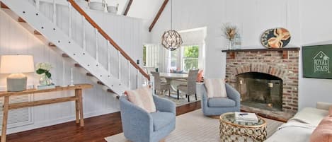 A spacious living room with a fireplace, a staircase, and a dining area.