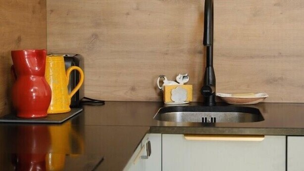 A kitchen with a sink, a red and yellow pitcher, a coffee maker, and a white mug on the counter. - Charming apartment in Rezé near Sèvre (Rezé)