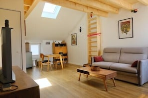 Ein Wohnzimmer mit Sofa, Tisch, Kamin und Dachfenster.