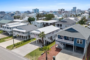 Un barrio residencial con varias casas de dos pisos, algunas con porches anexos y una vista despejada del océano al fondo.