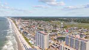 Un paisaje urbano costero con una playa, edificios de gran altura y un puerto deportivo.