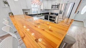 Une cuisine avec des armoires blanches, des appareils en acier inoxydable et un îlot central en bois doté de tabourets.