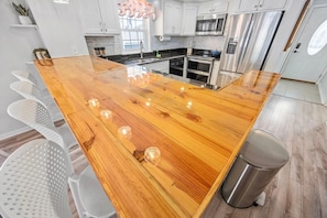 Una cocina con armarios blancos, electrodomésticos de acero inoxidable y una isla de madera con taburetes.