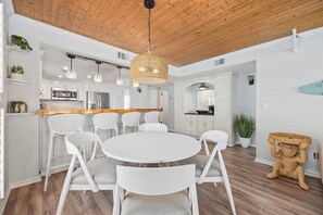 Une cuisine moderne avec des meubles blancs, un plafond en bois et des luminaires suspendus.