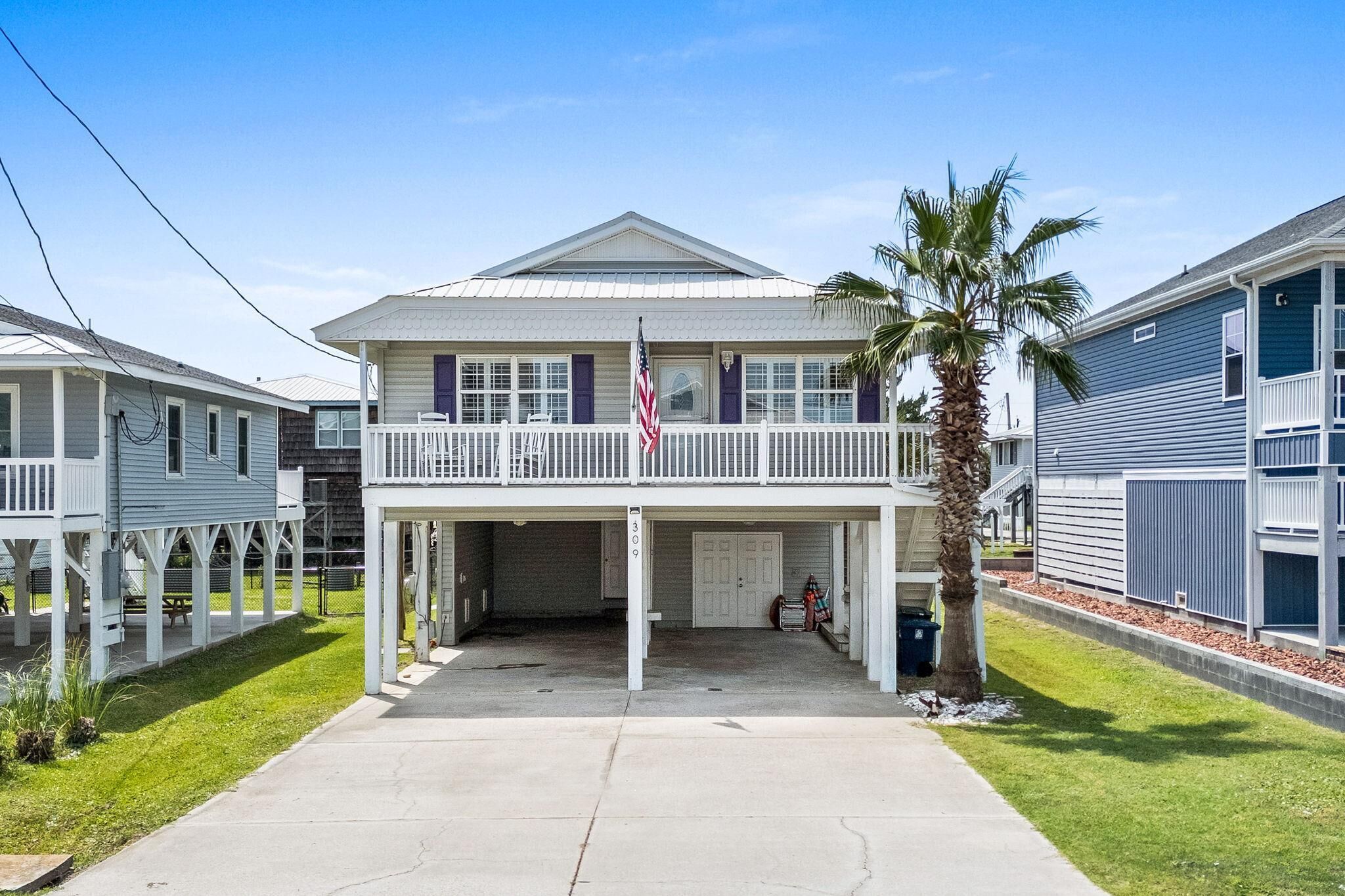 A two-story building with a balcony, a flag, and a palm tree.
