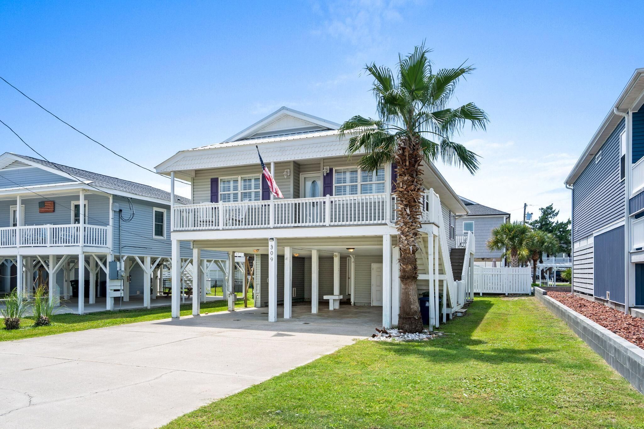 A two-story house with a balcony, a front porch, and a palm tree.
