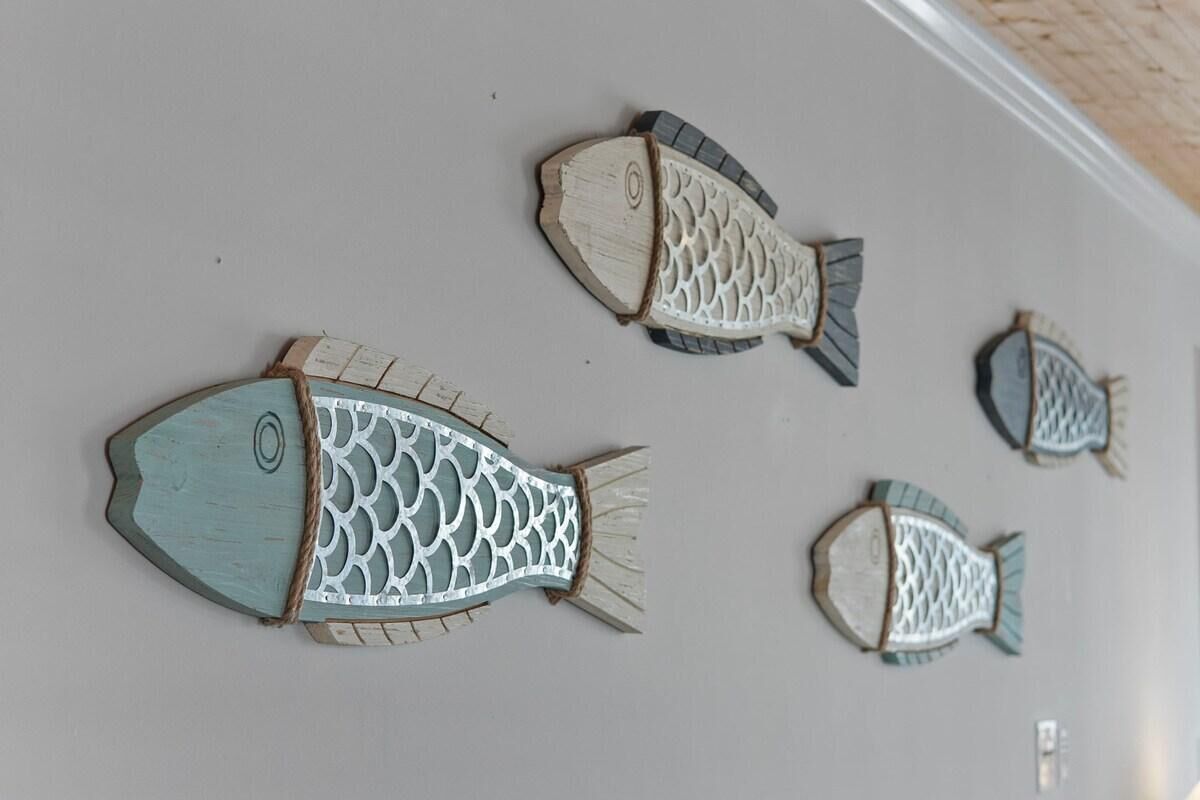 Four wooden fish wall art pieces on a plain wall.