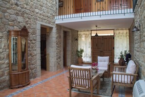 A stone-walled interior with a wooden dining set, two chairs, a table, and a large clock.