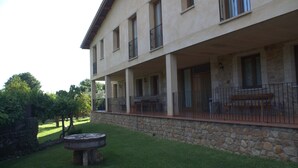 A two-story building with a stone facade, a covered outdoor seating area with tables and chairs, and a stone wall surrounding the property.