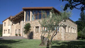 A stone building with large windows, a sloped roof, and a well-maintained lawn. - Rural House for Large Groups in Sierra de Gata, Cáceres, Extremadura (Cadalso)