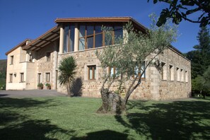 Un bâtiment en pierre doté de grandes fenêtres, d’un toit en pente et d’une pelouse bien entretenue.