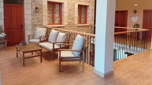 A cozy interior with a stone wall, wooden furniture, and a balcony with a railing.