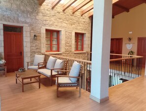 A cozy interior with a stone wall, wooden furniture, and a balcony with a railing.