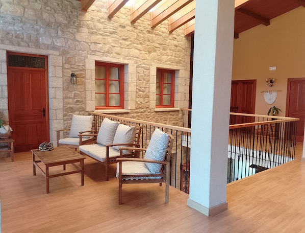 A cozy interior with a stone wall, wooden furniture, and a balcony with a railing.