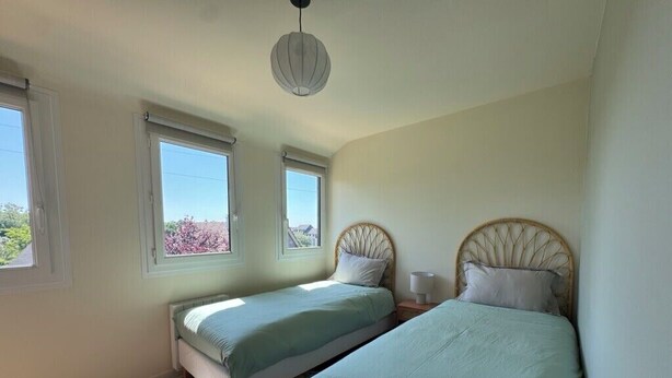 Ein Schlafzimmer mit zwei Betten, einem runden Teppich und einer Deckenleuchte.