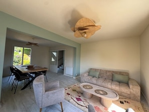 A spacious living area with a dining table, a sofa, and a coffee table. - Quiet house with garden, 5 min from Deauville (Touques)