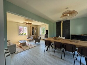 A spacious living area with a dining table, chairs, and a fireplace. - Quiet house with garden, 5 min from Deauville (Touques)