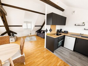 A modern kitchen with dark cabinets, a wooden countertop, and a built-in dishwasher. - A Cozy Nest Under the Roof (Wiwersheim)