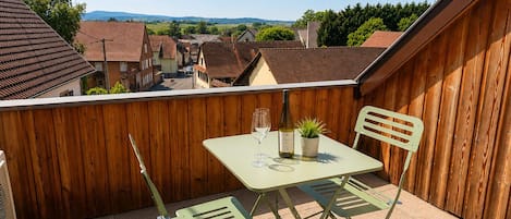 A balcony with a table and chairs, a bottle of wine, and a small plant.