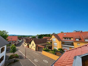 Eine Wohnstraße mit Häusern, blauem Himmel und einer fernen Bergkette.