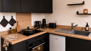 A modern kitchen with black cabinets, a stainless steel sink, a coffee maker, a toaster, and a dishwasher. - A Cozy Nest Under the Roof (Wiwersheim)