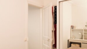 Et værelse med en dør til et skab, et spejl, en blød måtte og en reol med bøger og en lampe.