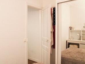 Ein Zimmer mit einer Tür zu einem Schrank, einem Spiegel, einem flauschigen Teppich und einem Regal mit Büchern und einer Lampe.