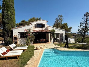 Ein Haus mit Swimmingpool, Liegestühlen und einer Terrassenfläche.