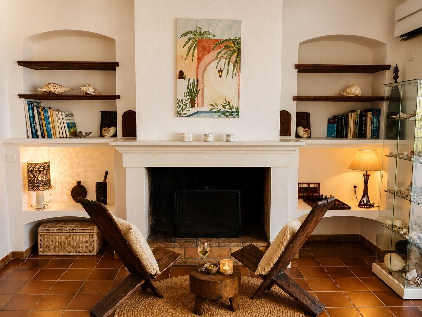 A living room with a fireplace, two armchairs, a coffee table, and shelves with books and decorative items.