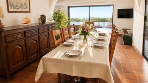 A dining area with a table set for six, a wooden cabinet, a plant, and a view through a glass door. - Villa with sea view and swimming pool in St-Aygulf (Fréjus)