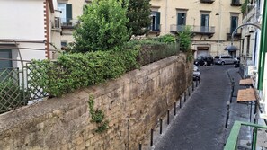 Eine schmale Stadtstraße, eine Seite begrenzt von einer Steinmauer, die andere Seite von Gebäuden.